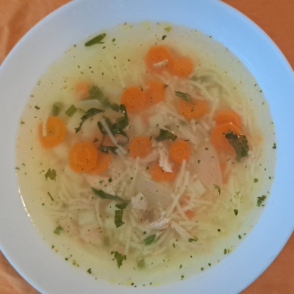 Homemade chicken vegetable soup served in a white bowl ready to enjoy.