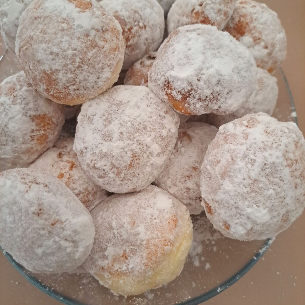 Vanilla sugar donuts served in a low glass dish, ready to enjoy fresh and sweet.