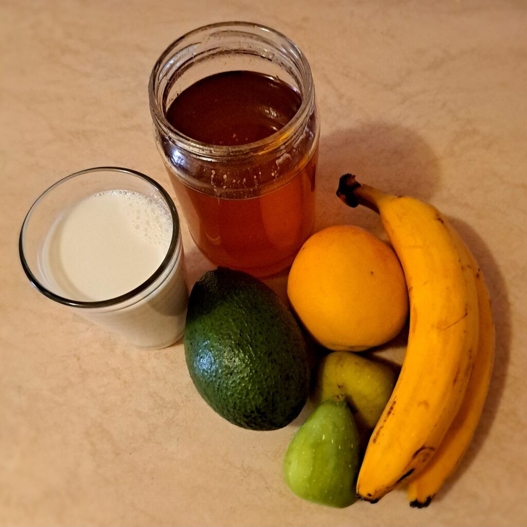 Avocado, peach, figs, bananas, honey, and milk ready for smoothie preparation.