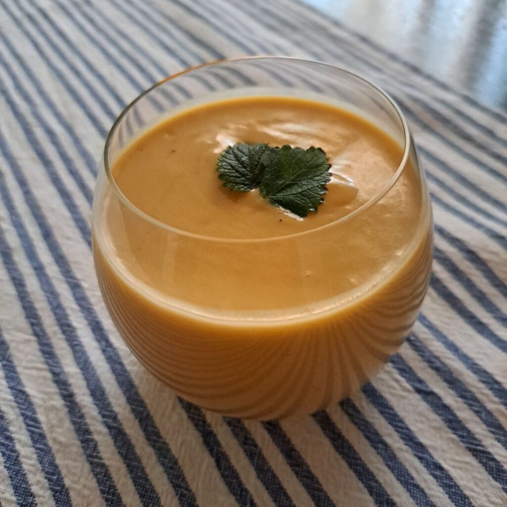 Avocado Fig Peach Smoothie served in low rounded glass with two mint leaves.