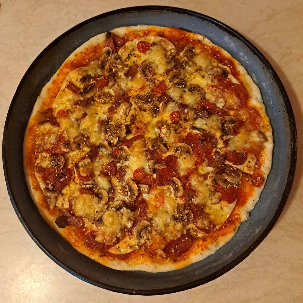 Top-down view of fully baked beef homemade pizza in a 38 cm pan, showing all layers and toppings.