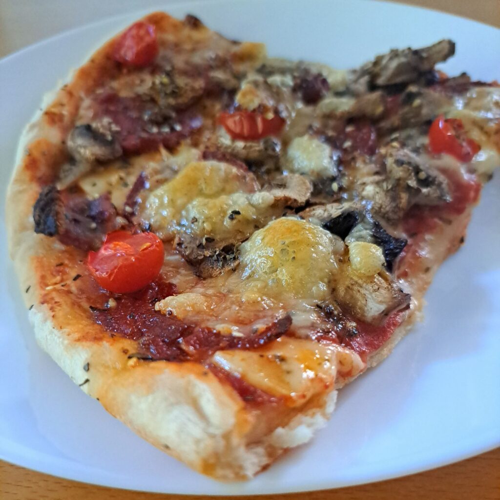 Close-up of one slice on a plate, highlighting melted cheese, meats, and fresh toppings.