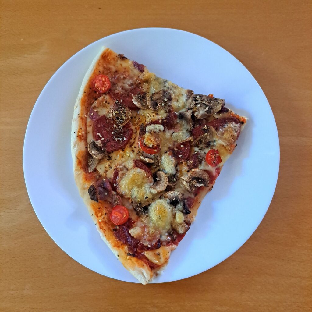 Top-down view of one slice of Beef Homemade Pizza Delight on a plate, ready to enjoy.