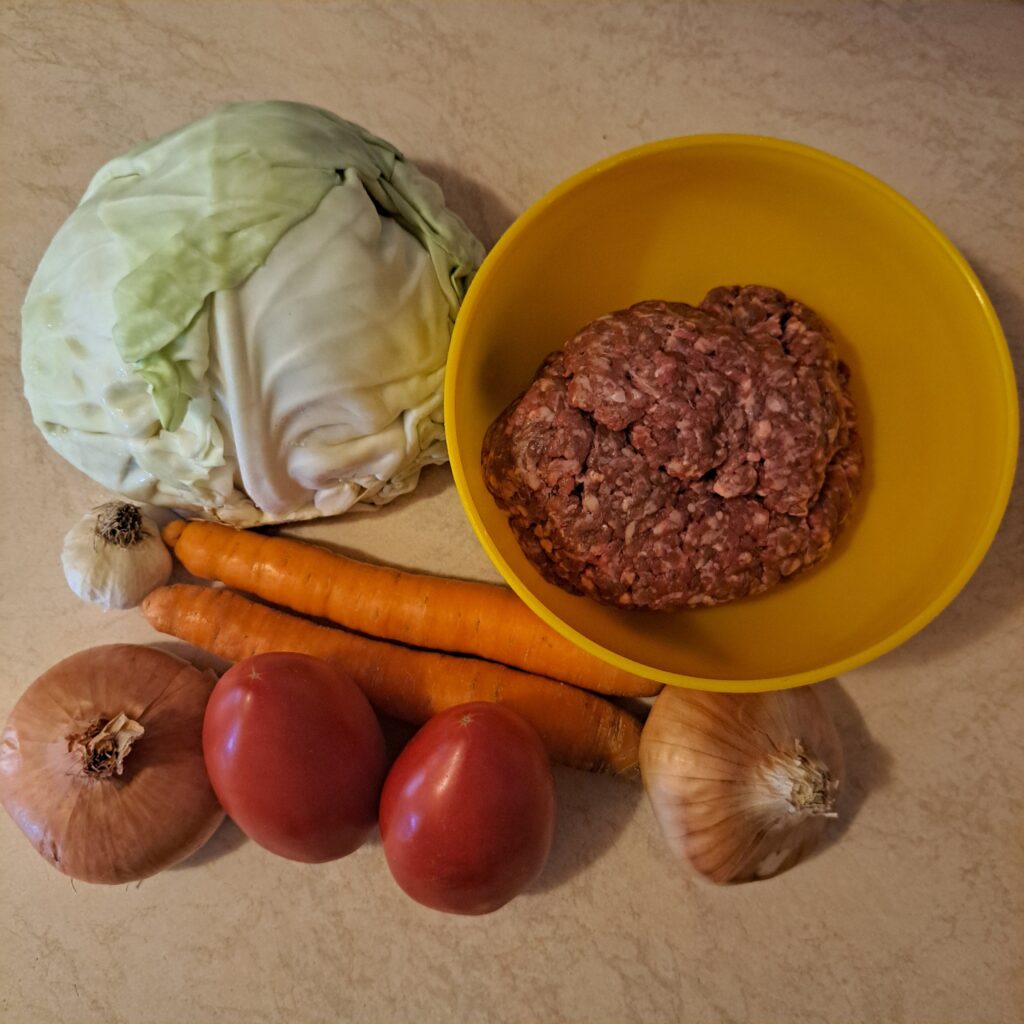 Whole cabbage, ground beef, carrots, onions, garlic, and tomatoes.