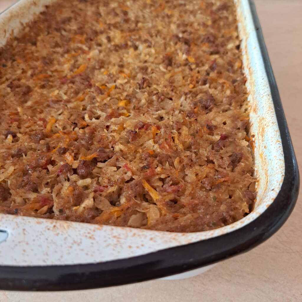 Ovenproof pan with baked cabbage, beef, and rice, side view close-up.