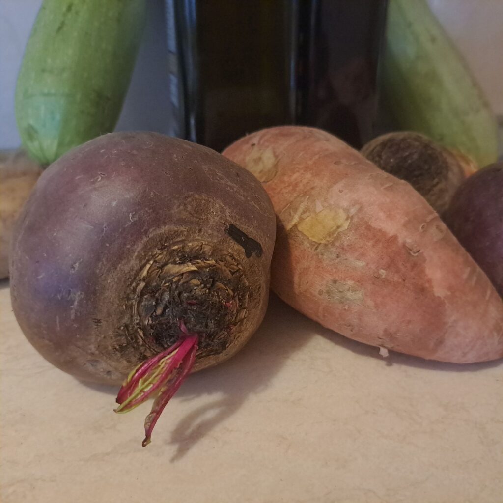 Whole beetroot and sweet potato with balsamic vinegar and olive oil in the background.