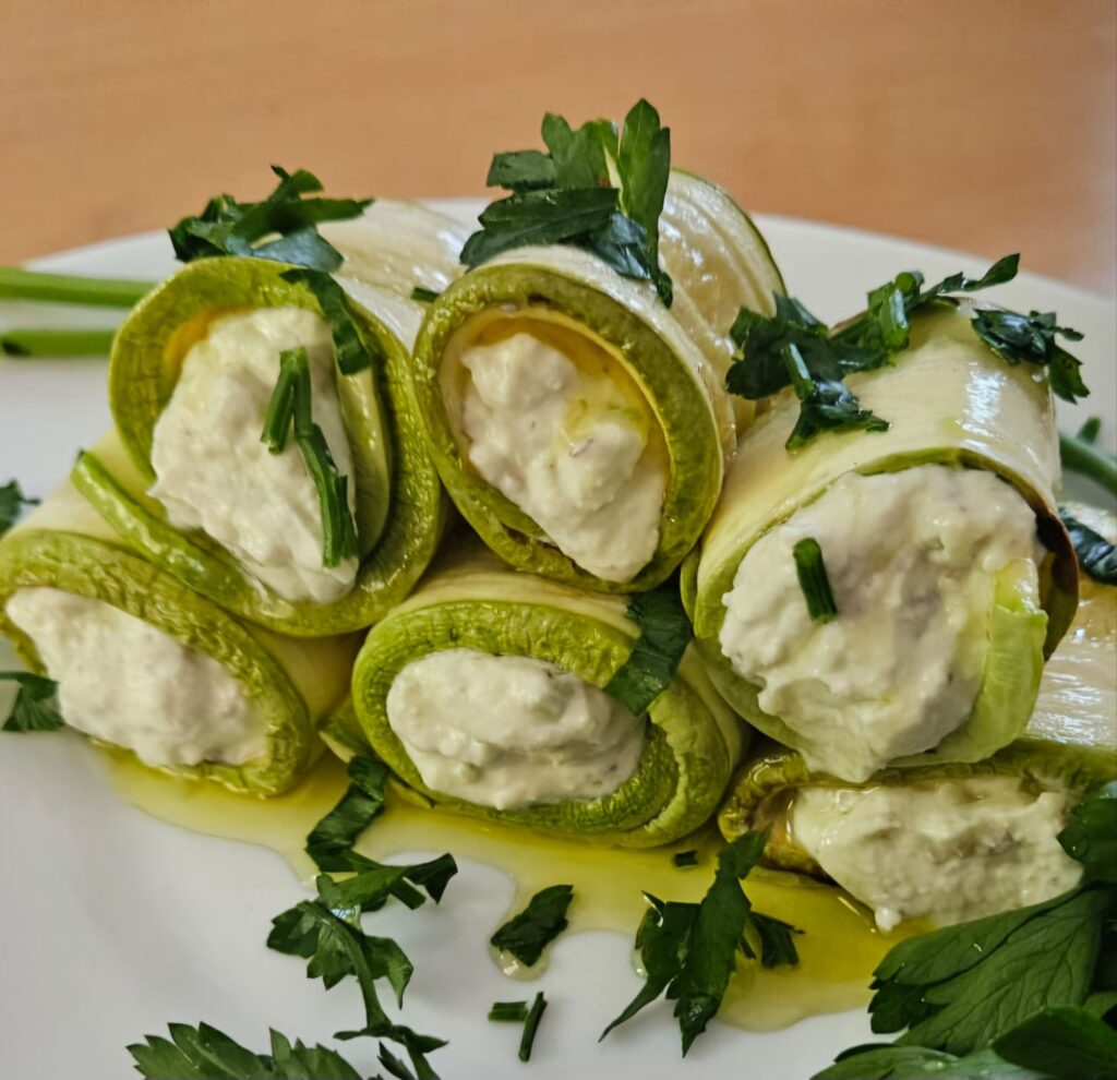 Rolled zucchini filled with creamy avocado mixture served on a plate, photographed from close up.