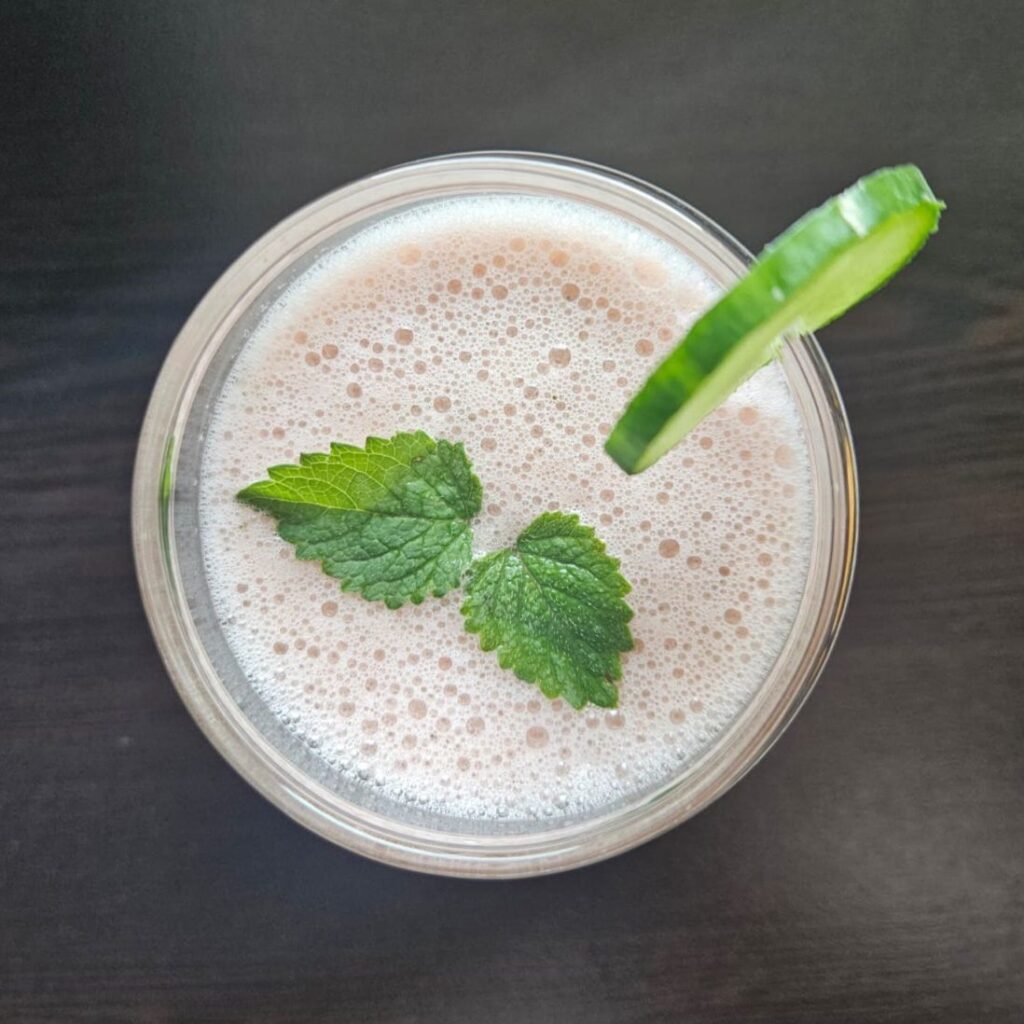 Overhead view of a glass with watermelon cucumber mint juice, decorated with cucumber slice and mint leaves.