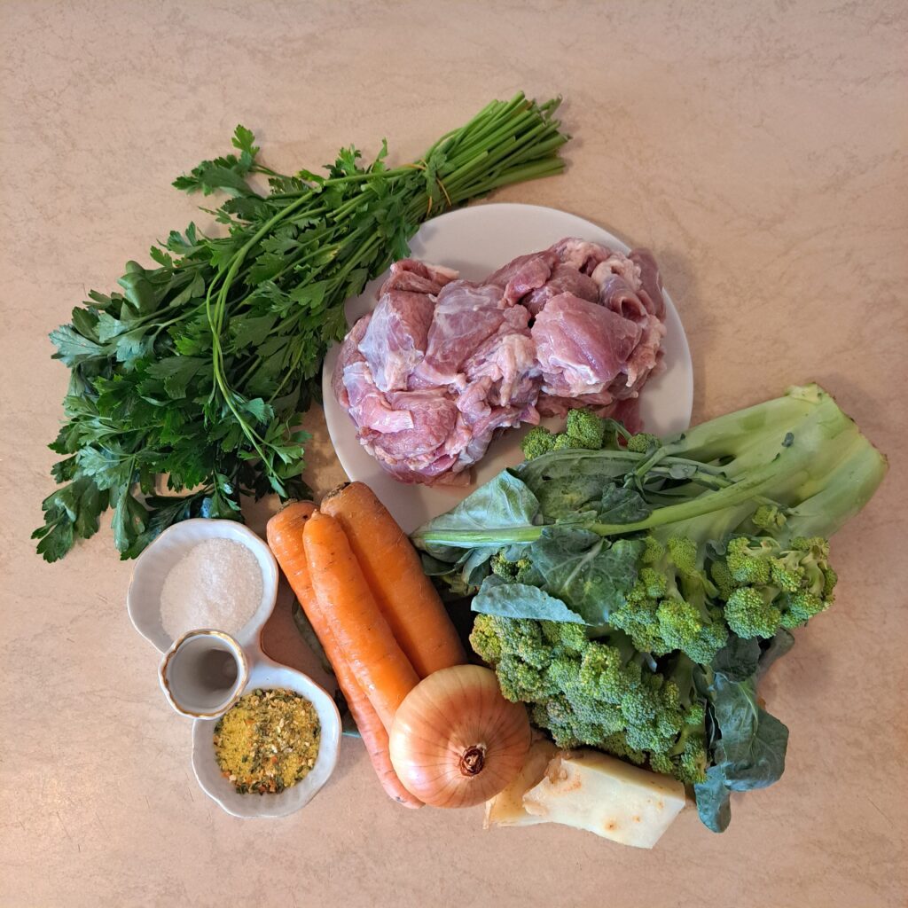 All ingredients for Pork Vegetable Noodle Soup arranged on a kitchen table, whole and uncut, ready for preparation.