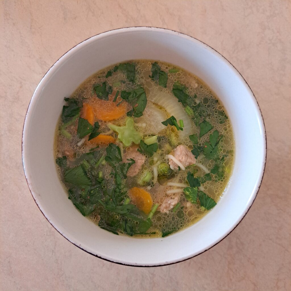 Pork Vegetable Noodle Soup served in a bowl, garnished with fresh parsley, viewed from above.
