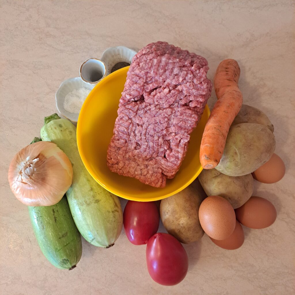 All ingredients for potato zucchini meat moussaka neatly prepared on the countertop.