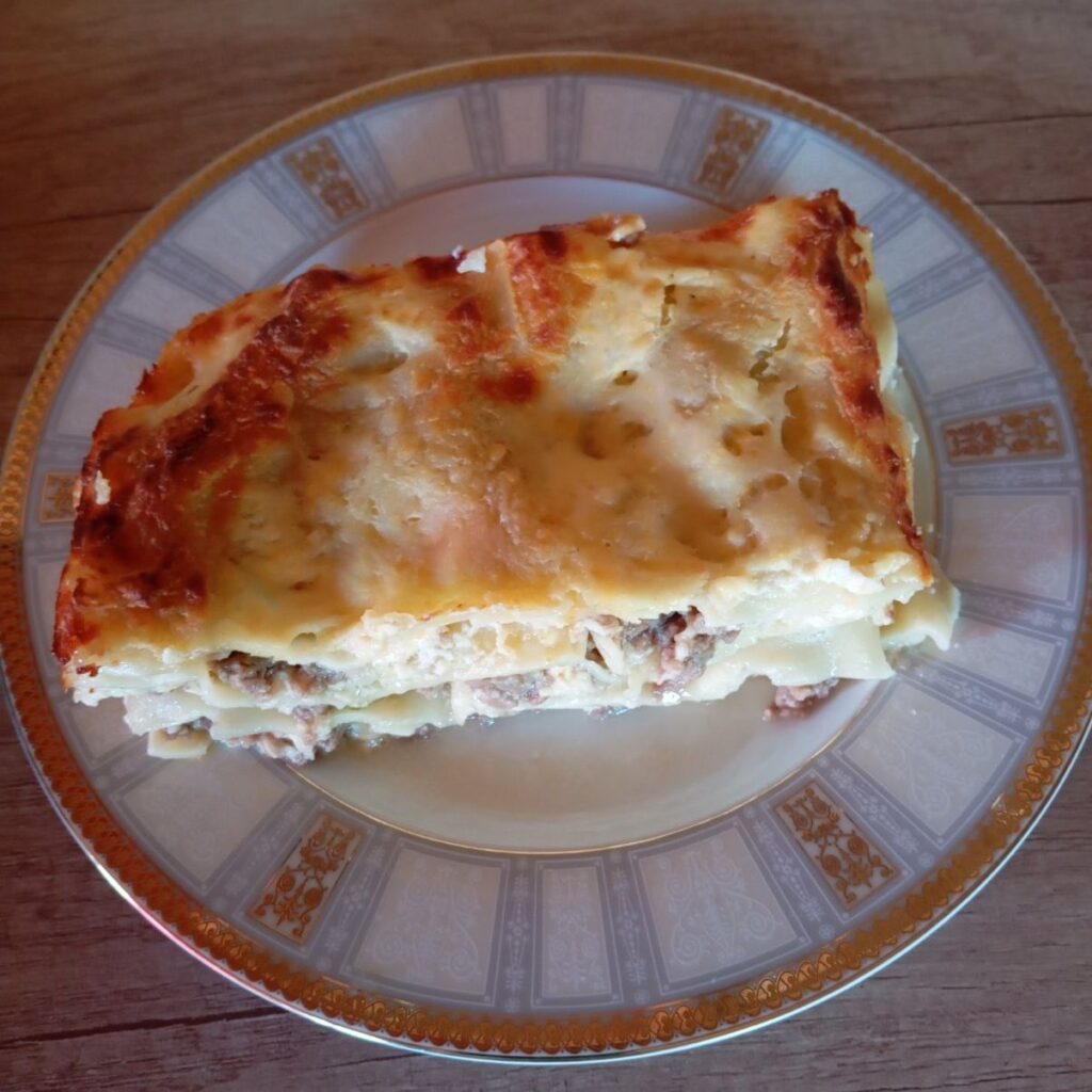 A slice of Homemade Meat Bechamel Lasagna served on a plate, ready to enjoy.