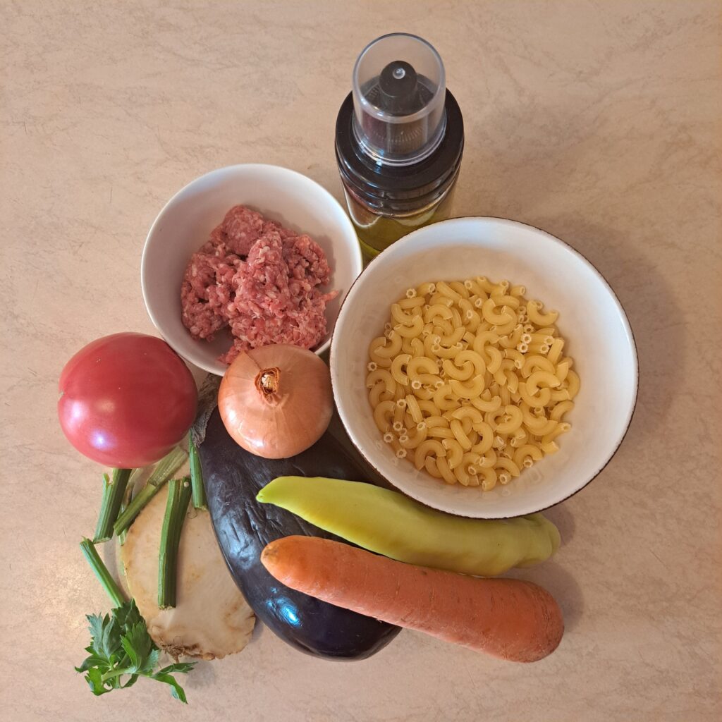 Close-up of fresh ingredients including ground beef, macaroni, and vegetables for soup.