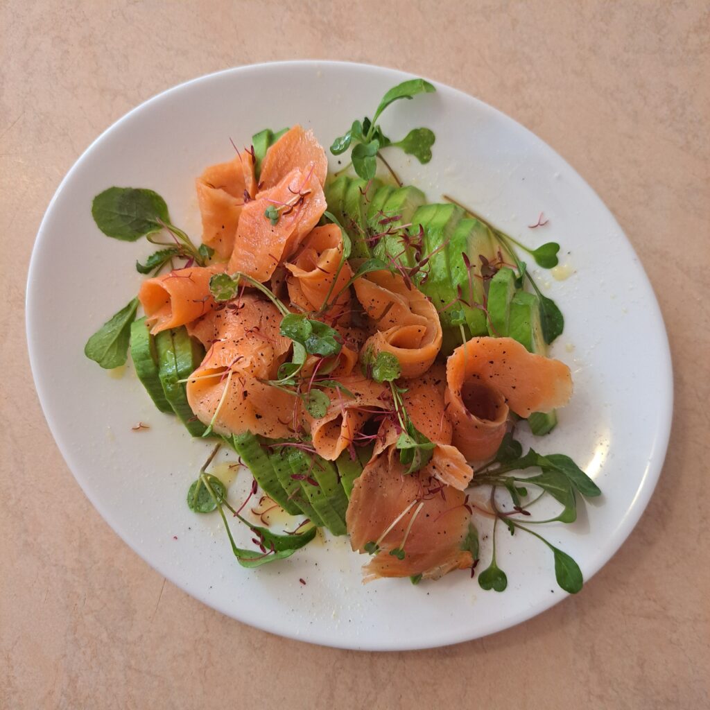 Full plate of avocado slices topped with smoked salmon and microgreens.