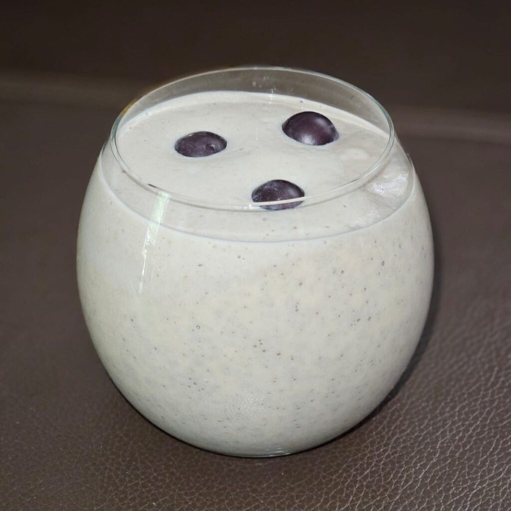 One low round glass with Baobab Avocado Banana Smoothie, topped with three grapes for decoration.