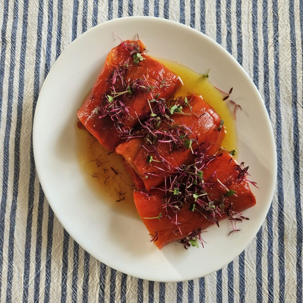 Plate of rolled roasted peppers decorated with microgreens.