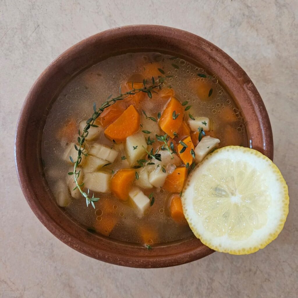 Root vegetable soup served in a bowl decorated with fresh thyme.