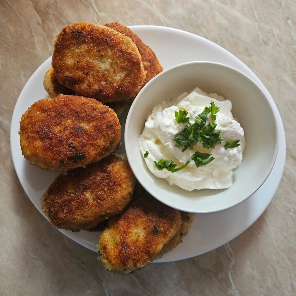Plate of golden chicken cauliflower bites served with sauce.