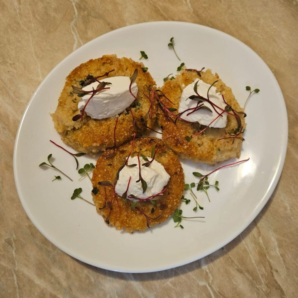 Quinoa cakes with cream cheese and microgreens arranged as the main recipe presentation.