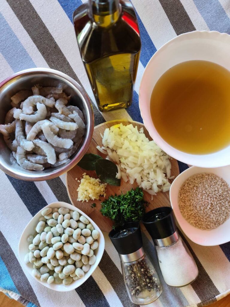 All ingredients for shrimp risotto on the counter, including cleaned shrimps, broad beans, rice, and prepared shrimp stock.