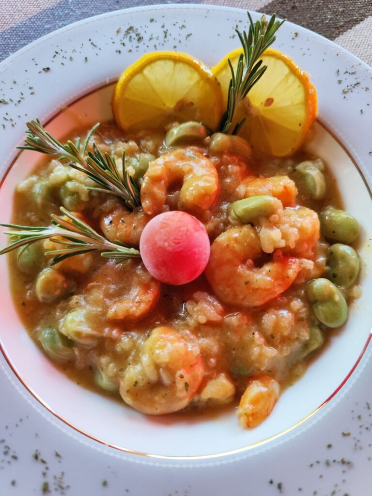 Close-up of a plate with creamy shrimp risotto and broad beans, ready to enjoy.