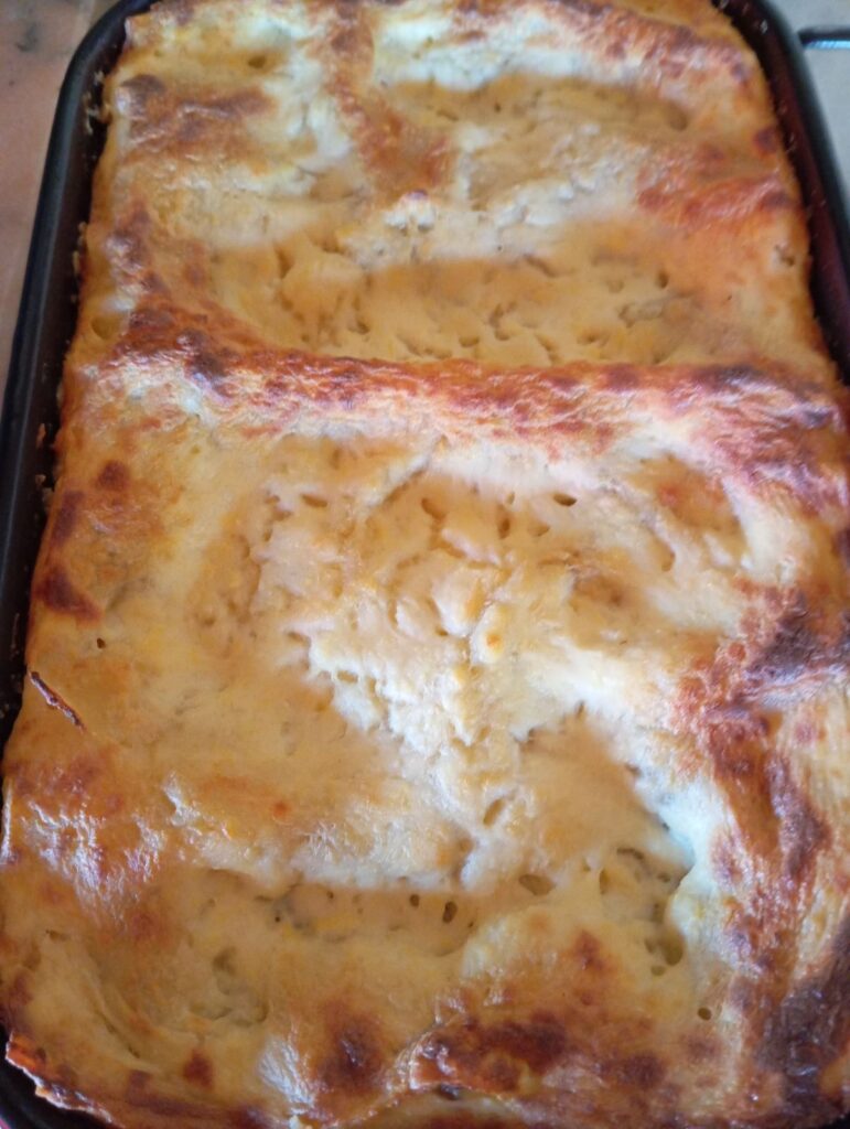 Homemade Meat Bechamel Lasagna fresh from the oven in a rectangular baking dish, golden and bubbly on top.