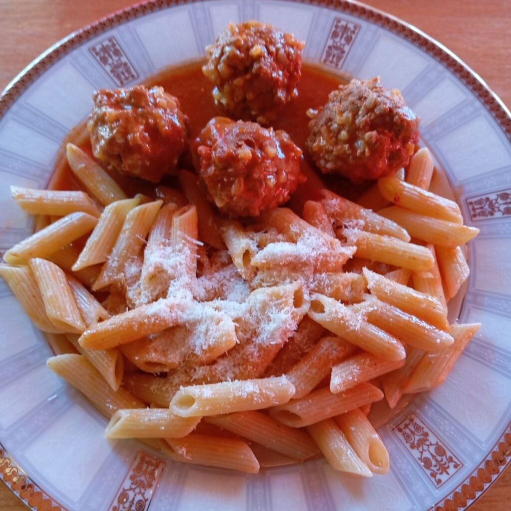 Served plate of Juicy Meatballs Tomato Sauce with cooked pasta and freshly grated Parmesan, ready to enjoy.