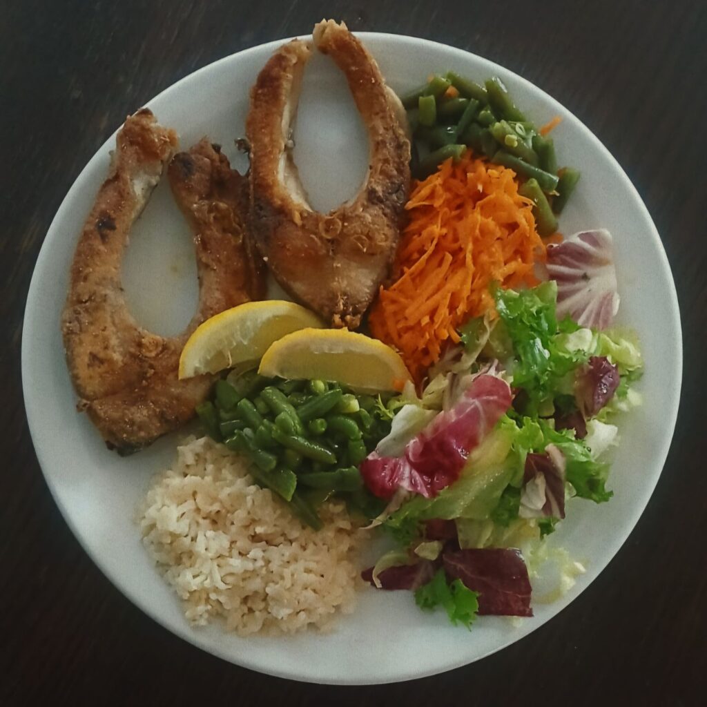 Served plate with carp, rice, beans, carrots, and salad.