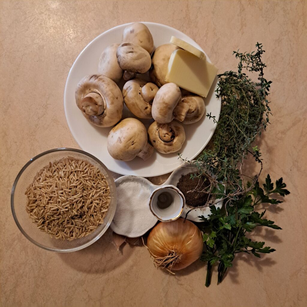 Ingredients on a table including mushrooms, onion, garlic, wild rice, parsley, thyme, salt, and pepper.