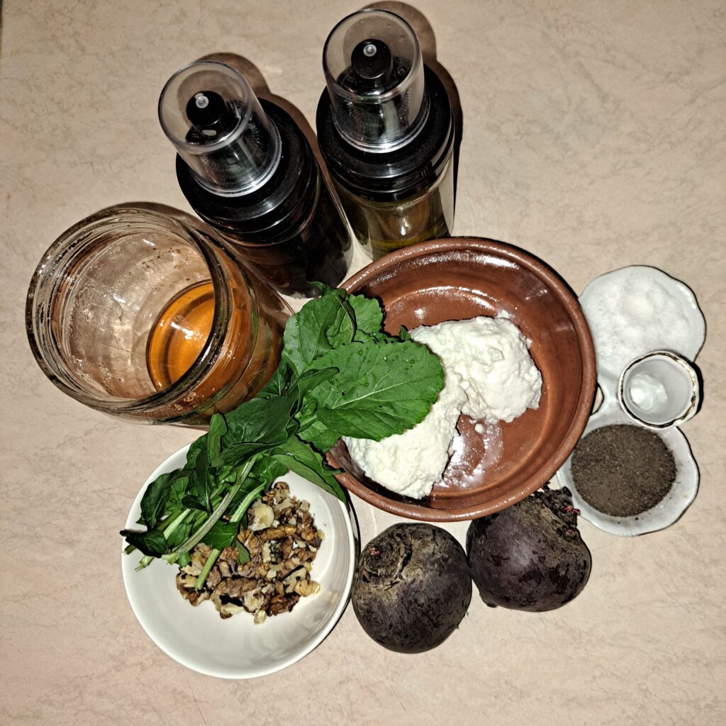 Fresh ingredients for beetroot salad including beets, goat cheese, walnuts, arugula, honey, olive oil, and balsamic vinegar.