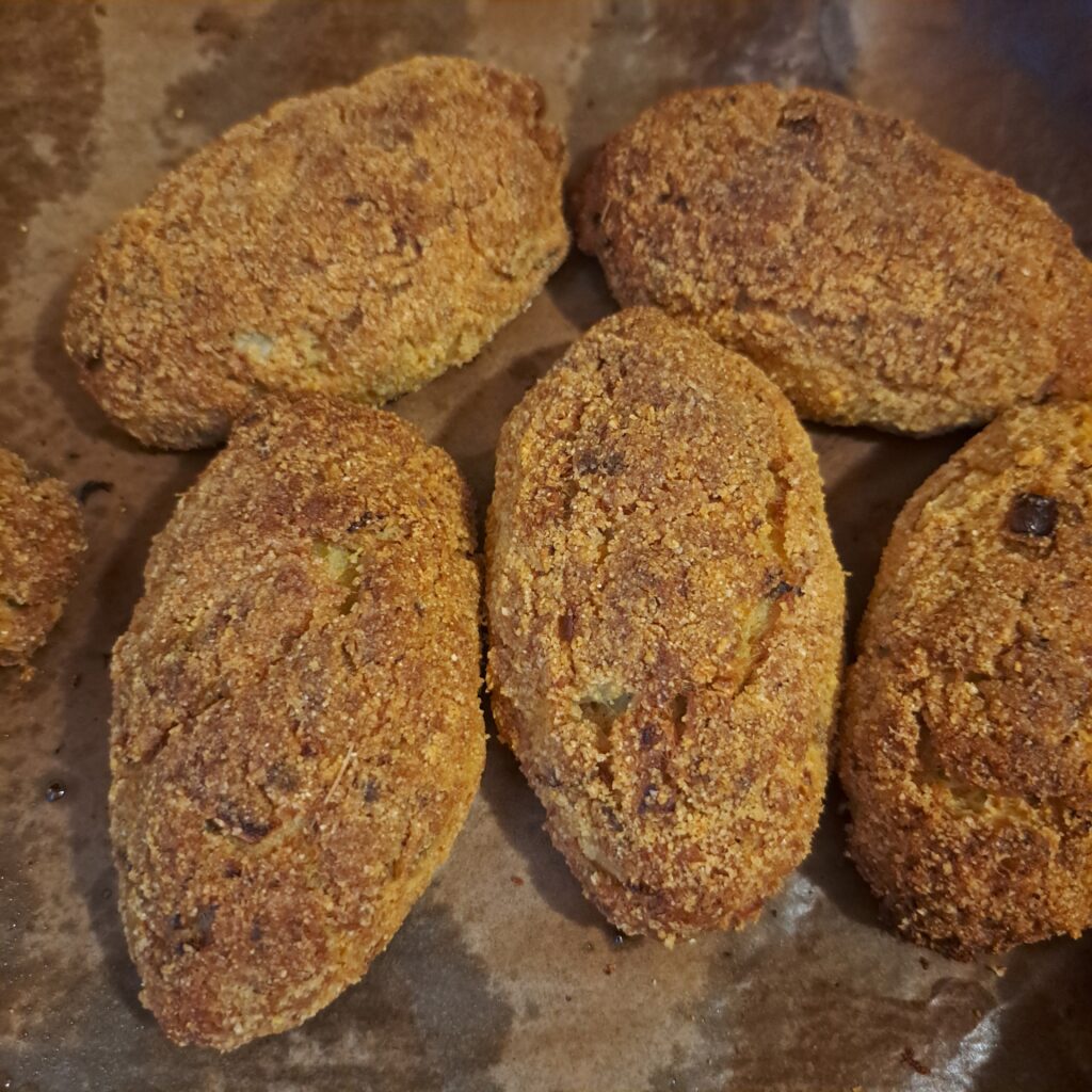 Crispy mackerel cauliflower patties baked on parchment paper in a baking tray.