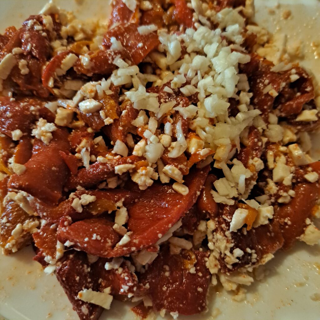 Preparing the mix with goat cheese, chopped fermented red peppers, minced garlic, and olive oil in a bowl.