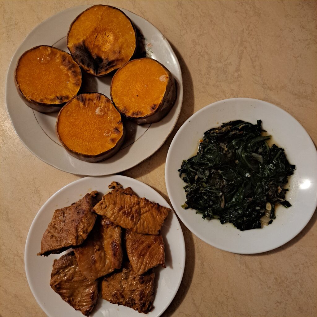 Roasted butternut squash rounds, fried pork loin slices, and boiled chard with chopped garlic arranged together as main ingredients.