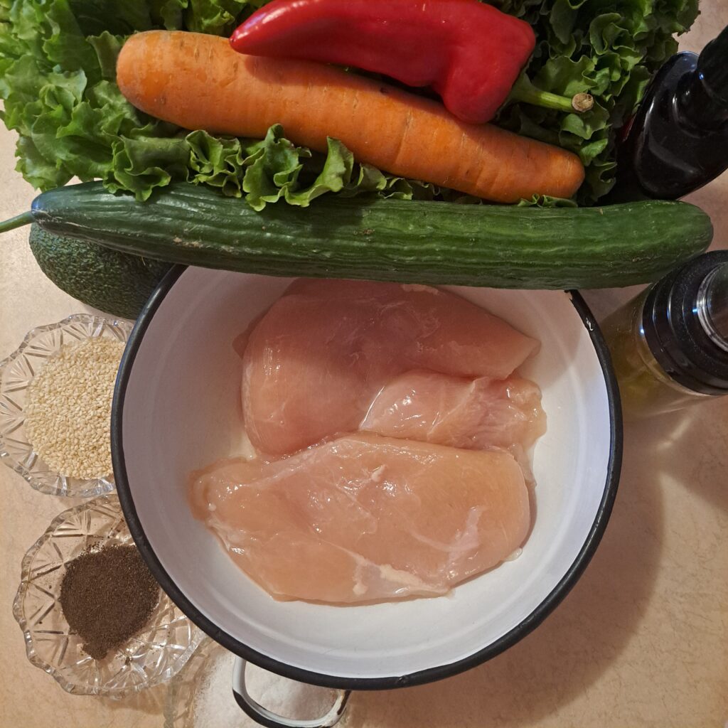 Ingredients for chicken and vegetable wraps with lettuce, avocado, carrot, cucumber, and red pepper.