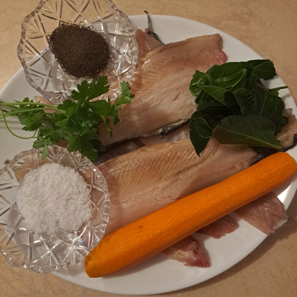 Fresh ingredients: fish fillets, spinach, carrot, salt, and pepper in a plate. 