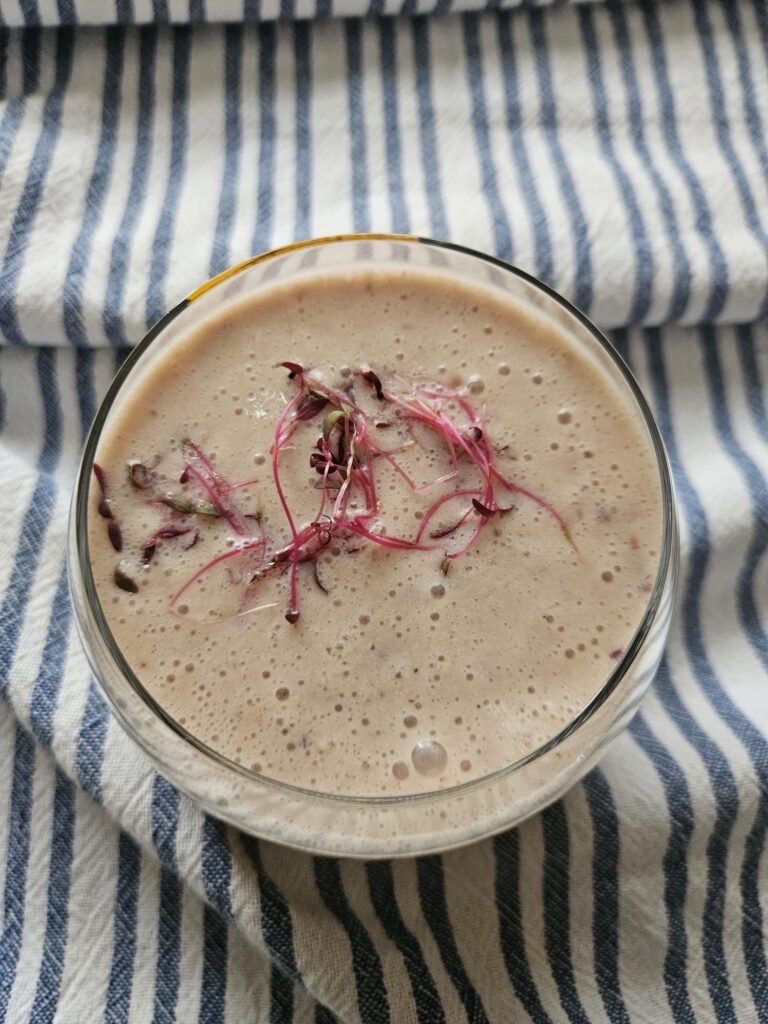 Top view of Apple Banana Amaranth Smoothie served in a round low glass with smooth creamy texture.
