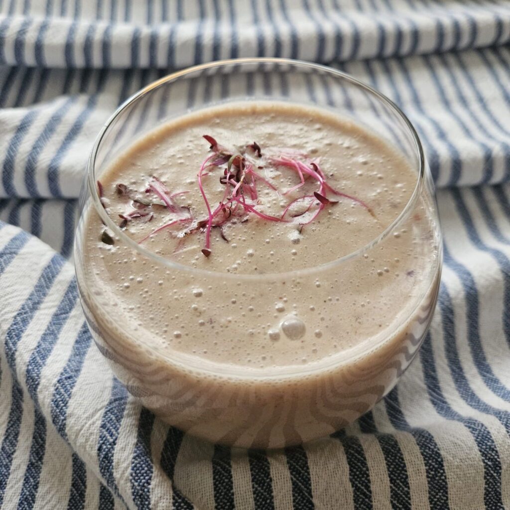 Apple Banana Amaranth Smoothie served in a glass, decorated with fresh amaranth microgreens.