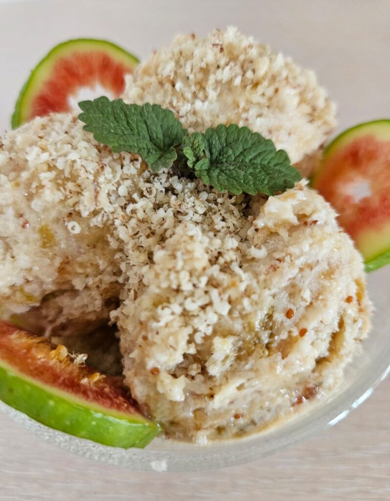 Close-up of three scoops of green fig ice cream topped with ground walnuts.