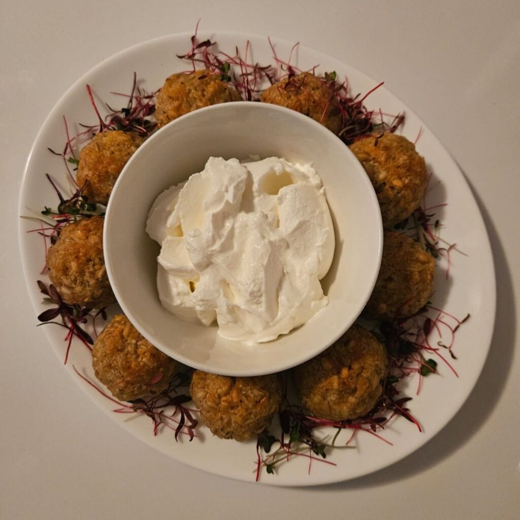 Top view of barley risotto bites served with mixed microgreens and creamy white yogurt sauce.
