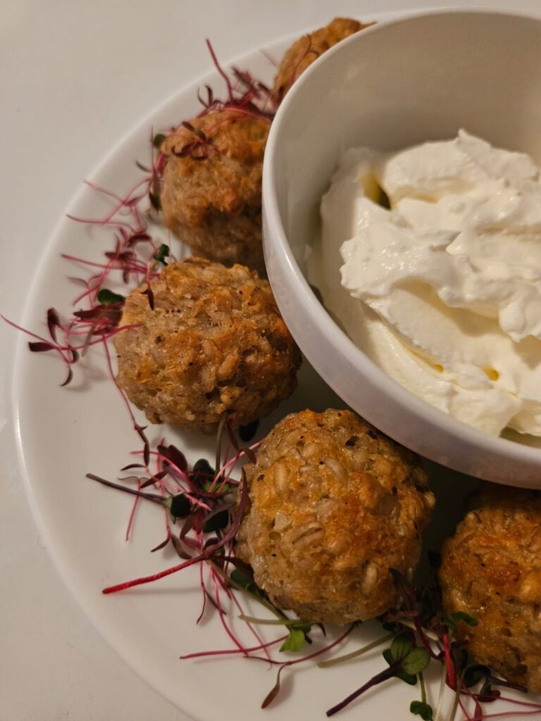 Crispy barley risotto bites served on a white plate with yogurt lemon garlic sauce in the center.