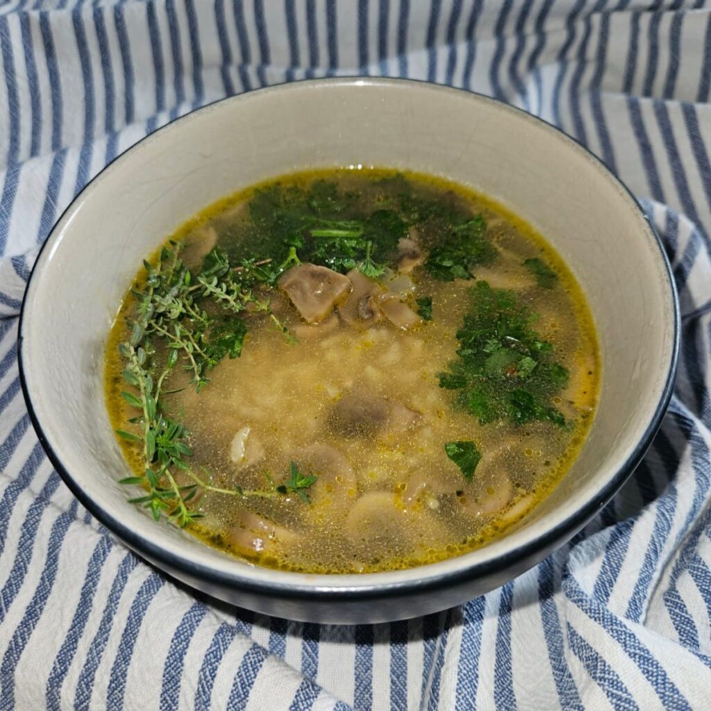 Bowl of Mushroom and Wild Rice Soup garnished with fresh parsley and thyme.