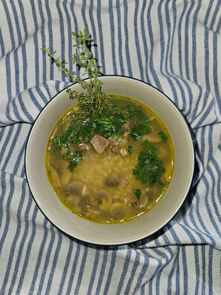 Overhead view of Mushroom and Wild Rice Soup served in a bowl with parsley and thyme.
