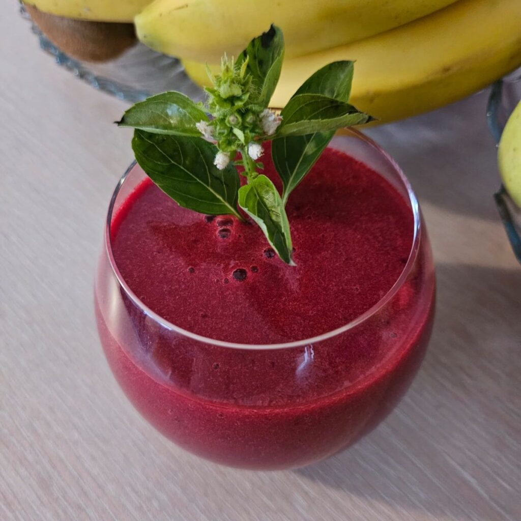 A served glass of Beetroot Peach Basil Juice garnished with fresh basil for a natural look.
