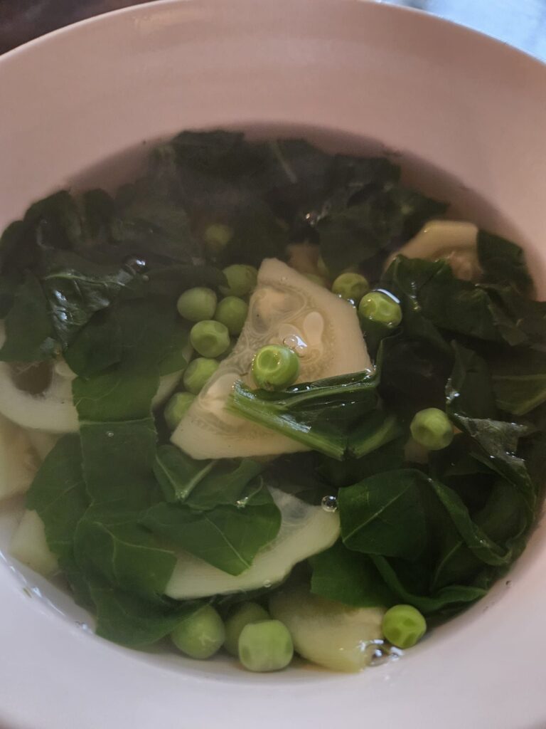 Close-up top view of spinach, zucchini, and pea soup served in a bowl.