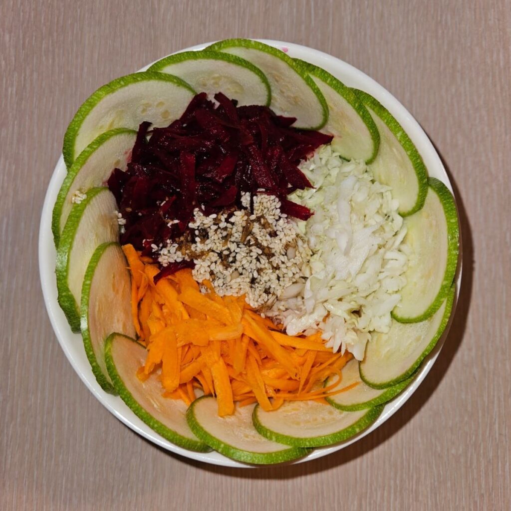 Bowl of colorful vegetable salad with dressing made from sesame oil, ginger, and soy sauce.