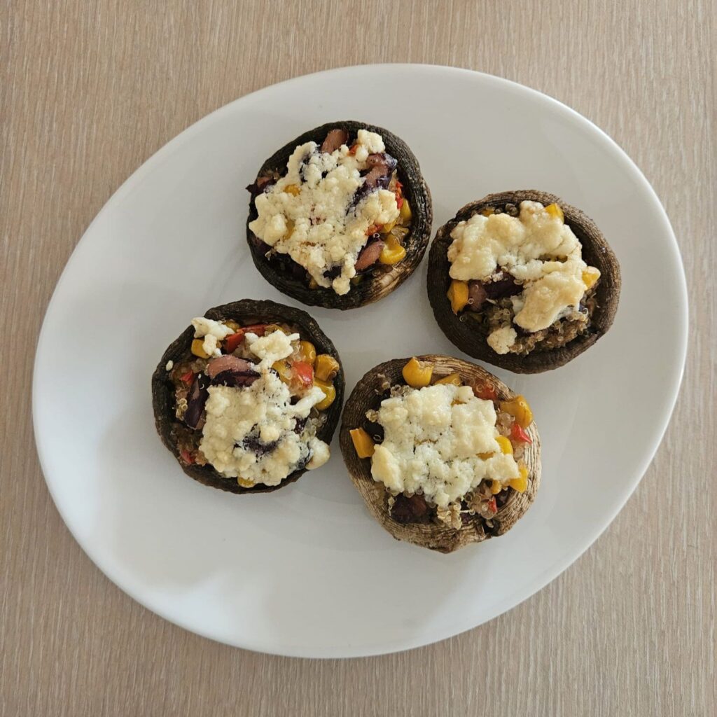 Four Quinoa Stuffed Mushrooms with Cheese served on a flat plate.