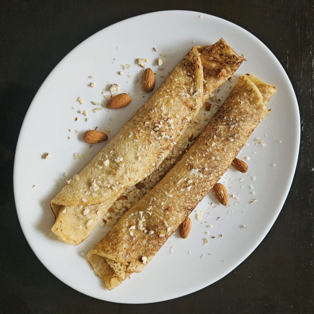 Whole Wheat Crepes with Apricot Jam and Almonds topped with finely chopped almonds, photographed from above.