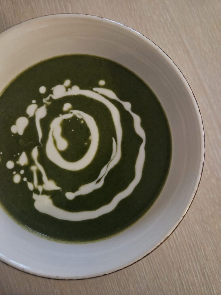 Close-up view of creamy broccoli spinach yogurt soup served in a bowl, showing its smooth green texture.
