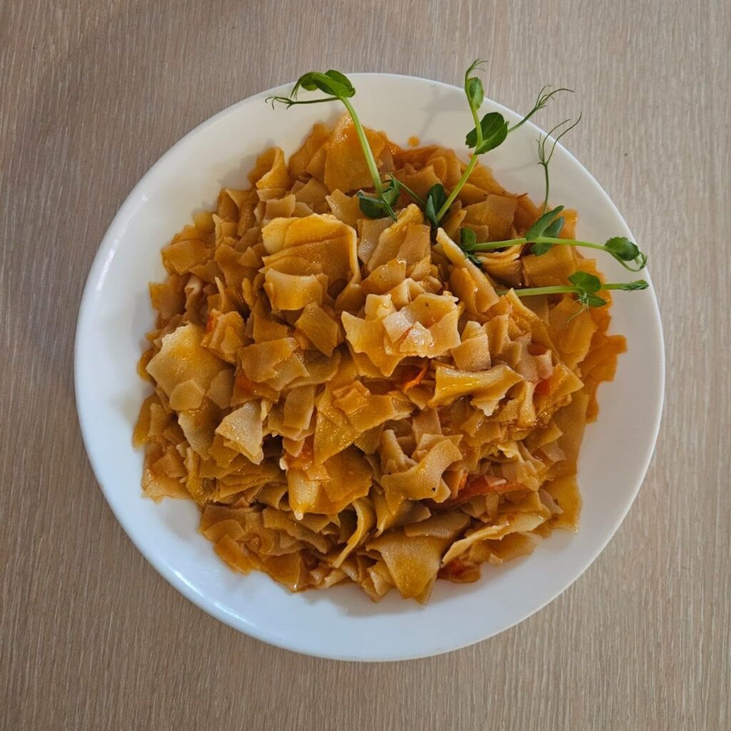 Homemade Dried Pasta Delight served on a plate, topped with a few fresh pea microgreens for color and decoration.