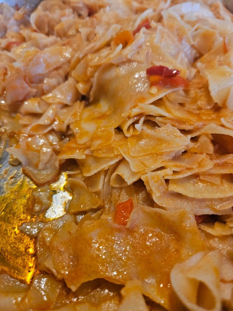 A close-up view of Homemade Dried Pasta Delight served in a pan, showing its rich texture and golden color.